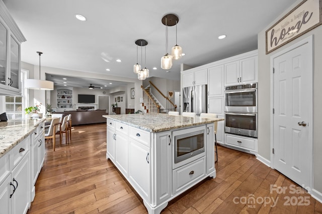 1108 Longwood Ct, Matthews, NC 28104 - kitchen with stainless steel appliances, open floor plan, light wood-style floors, glass insert cabinets, and white cabinets