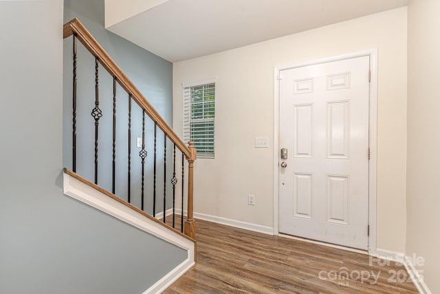 foyer with wood finished floors, stairway, and baseboards