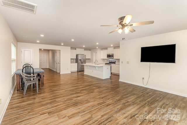 living room featuring a ceiling fan, light wood-style floors, recessed lighting, and baseboards