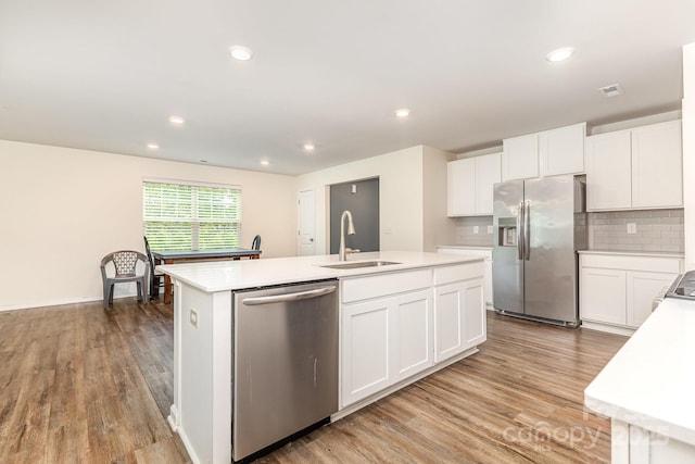kitchen with appliances with stainless steel finishes, a sink, a center island with sink, light wood-type flooring, and recessed lighting