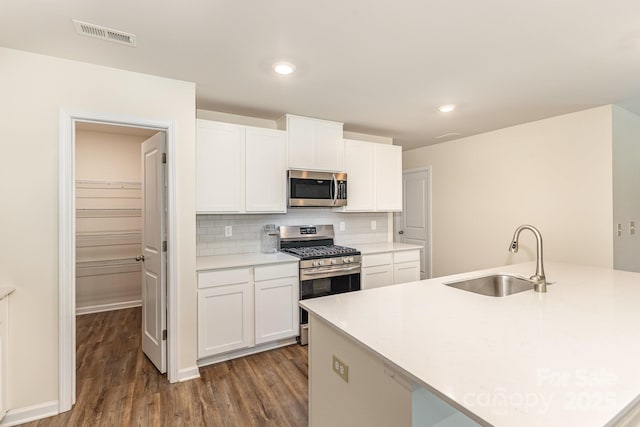 kitchen featuring stainless steel appliances, a sink, dark wood-style floors, white cabinetry, and recessed lighting