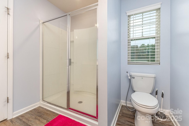 full bathroom with wood finished floors, a shower stall, toilet, and baseboards