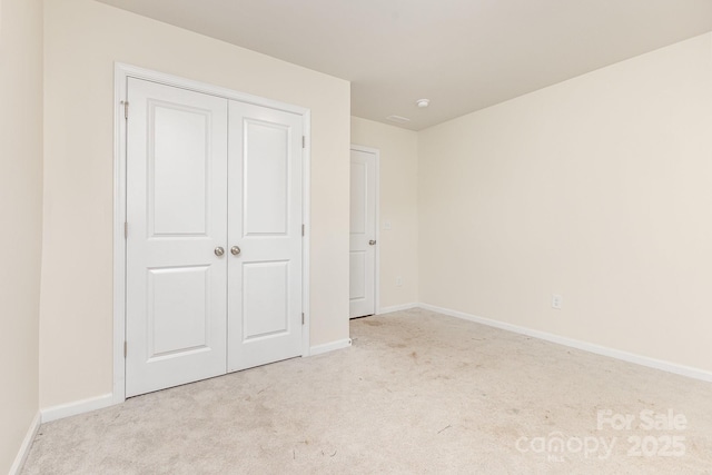 unfurnished bedroom featuring carpet floors, baseboards, and a closet