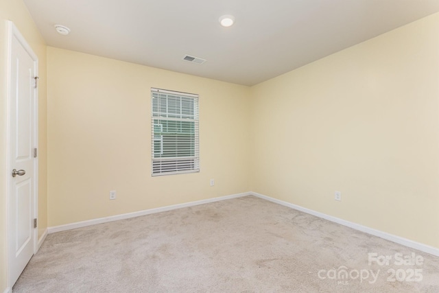 empty room featuring light carpet, baseboards, and a smoke detector