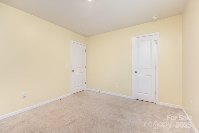 empty room with light colored carpet and baseboards
