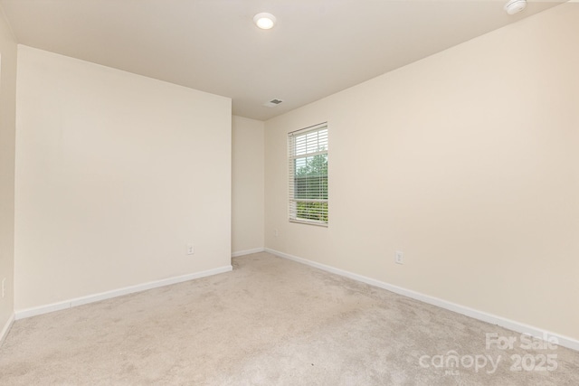 unfurnished room with light colored carpet and baseboards