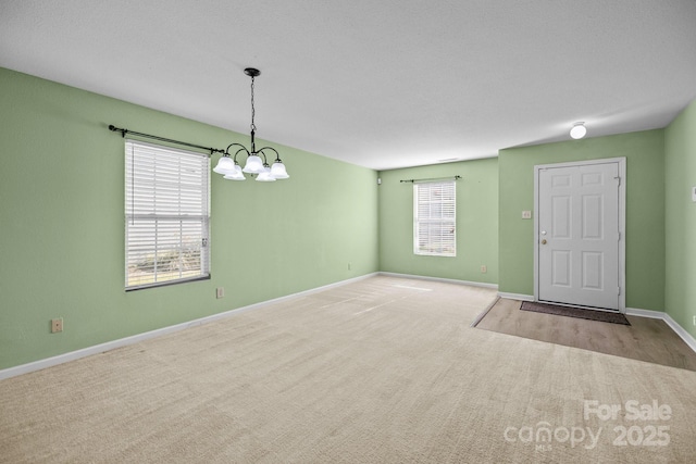 empty room featuring carpet, a chandelier, and baseboards