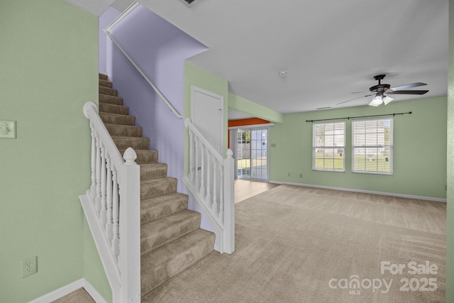 staircase with ceiling fan, baseboards, and carpet flooring