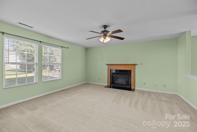 unfurnished living room with a fireplace with flush hearth, carpet flooring, ceiling fan, and baseboards