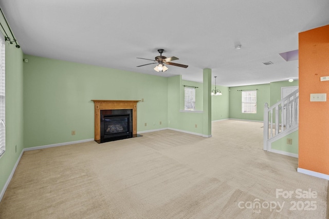 unfurnished living room featuring carpet floors, a fireplace with flush hearth, ceiling fan, and baseboards