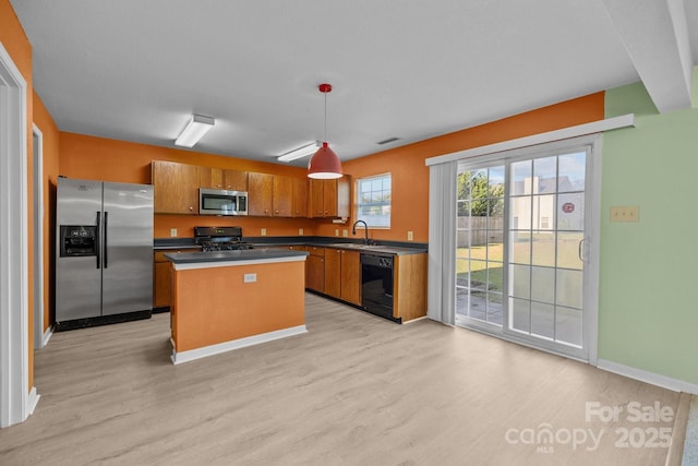 kitchen with stainless steel appliances, light wood-style floors, brown cabinets, and a center island
