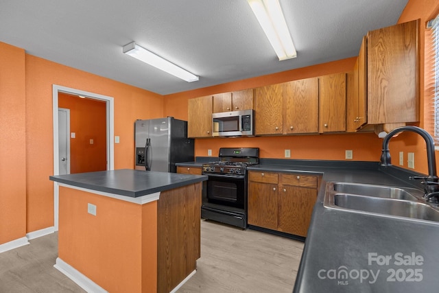 kitchen featuring black gas range, stainless steel microwave, refrigerator with ice dispenser, a sink, and dark countertops