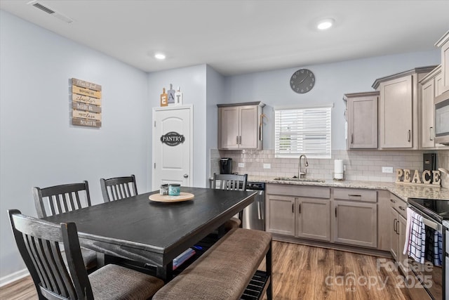 kitchen with a sink, tasteful backsplash, visible vents, dark wood-style flooring, and appliances with stainless steel finishes
