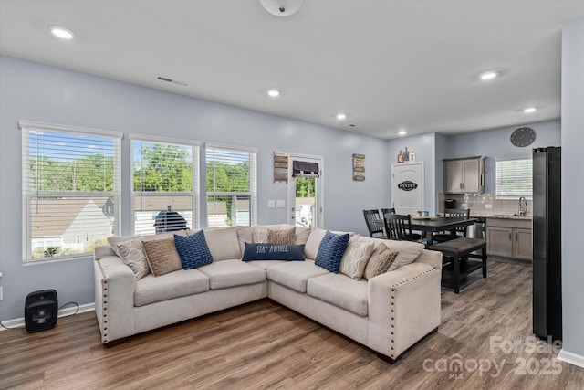 living area with a healthy amount of sunlight, light wood-style flooring, and visible vents