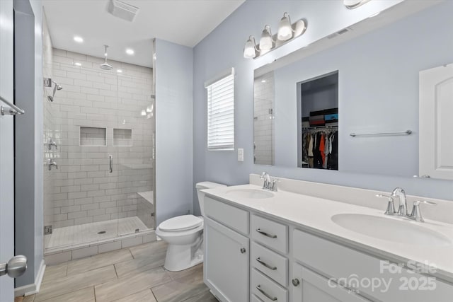 full bath with toilet, visible vents, a shower stall, and a sink