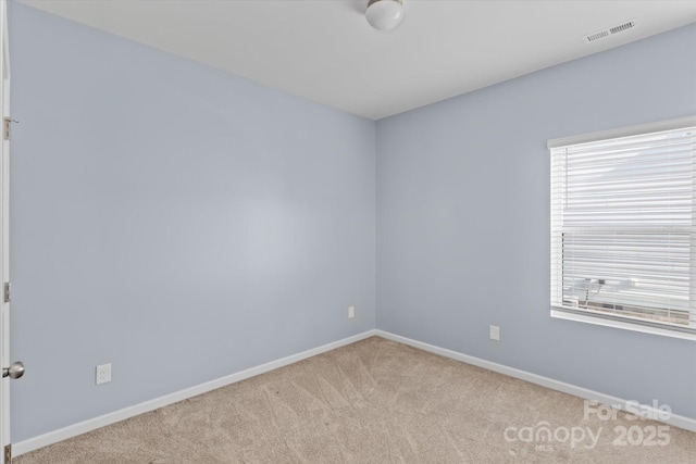 spare room with carpet floors, baseboards, and visible vents