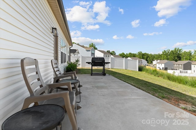view of patio with grilling area, fence, and a residential view