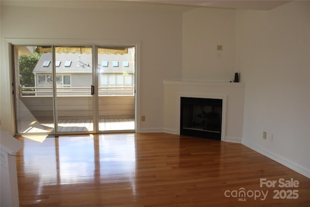 unfurnished living room with a fireplace, baseboards, and wood finished floors
