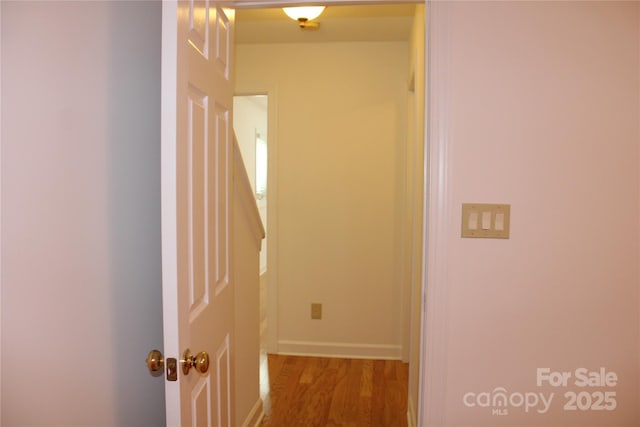 hall with baseboards and wood finished floors