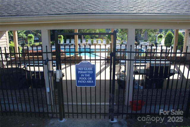view of gate with fence private yard and a community pool