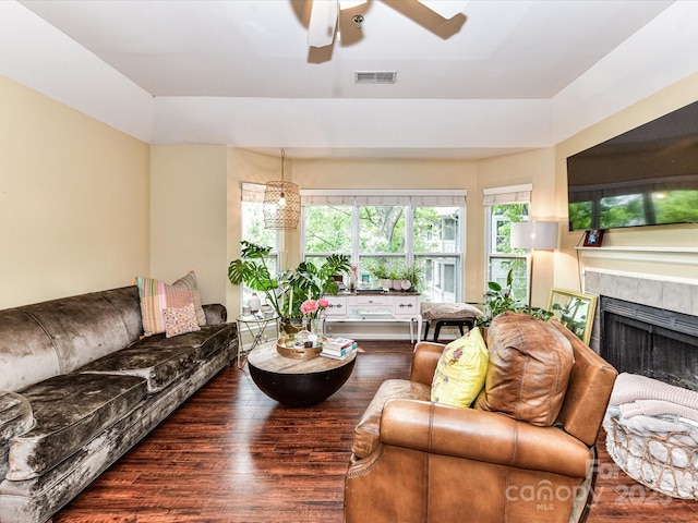 living area featuring ceiling fan, wood finished floors, and a tiled fireplace