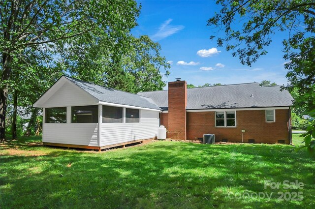 back of property featuring crawl space, a chimney, a lawn, and central AC
