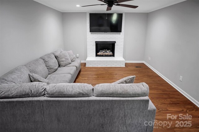 living area featuring ceiling fan, wood finished floors, recessed lighting, a fireplace, and ornamental molding