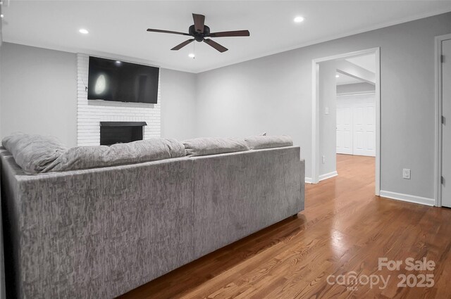 unfurnished living room with ceiling fan, wood finished floors, a fireplace, recessed lighting, and baseboards