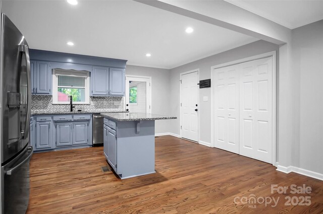 kitchen with fridge with ice dispenser, gray cabinetry, a kitchen island, tasteful backsplash, and stainless steel dishwasher