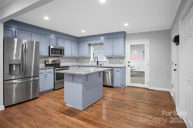 kitchen featuring appliances with stainless steel finishes, decorative backsplash, a center island, a sink, and recessed lighting