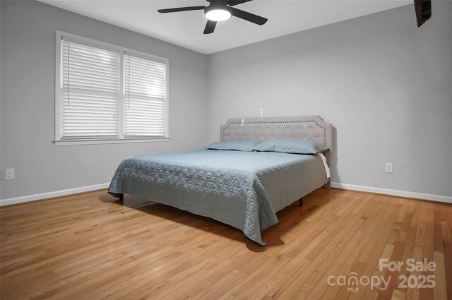 bedroom featuring baseboards, wood finished floors, and ceiling fan