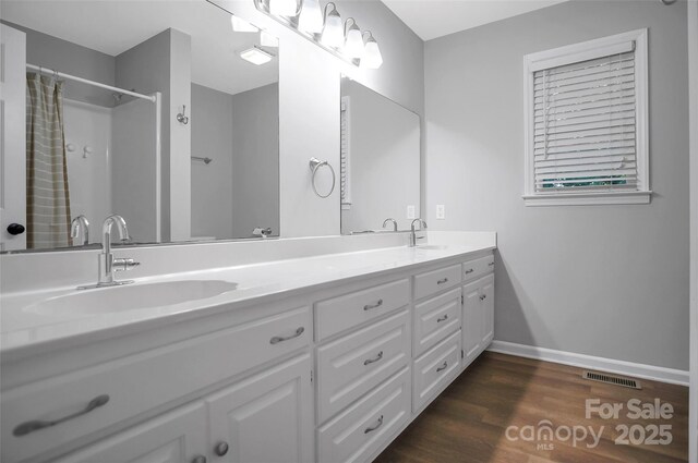 bathroom featuring double vanity, baseboards, wood finished floors, and a shower with curtain