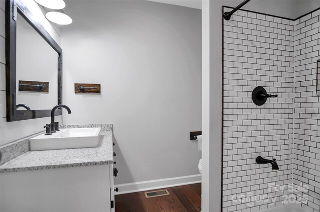 full bath featuring vanity, wood finished floors, baseboards, toilet, and bathtub / shower combination