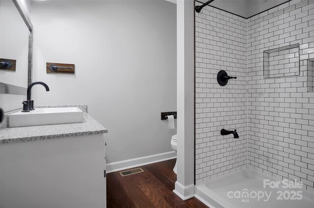 bathroom featuring wood finished floors, toilet, a shower stall, vanity, and baseboards