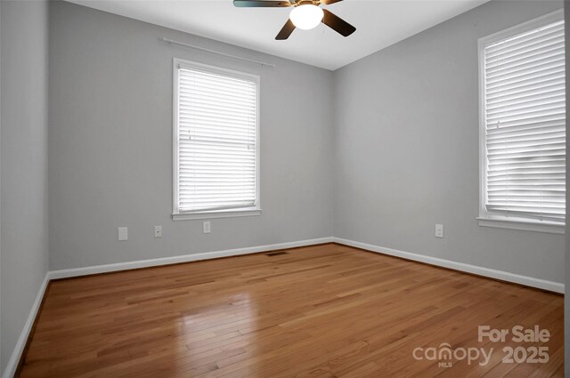 unfurnished room with a ceiling fan, wood finished floors, and baseboards