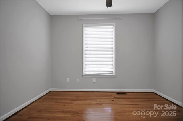 unfurnished room featuring plenty of natural light, baseboards, and wood finished floors