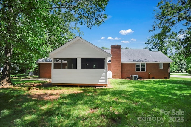 rear view of property with a chimney, a yard, crawl space, and central AC