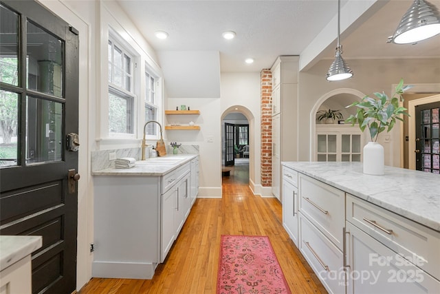 118 Macon Ave, Asheville, NC 28801 - kitchen with arched walkways, a sink, light wood finished floors, baseboards, and pendant lighting