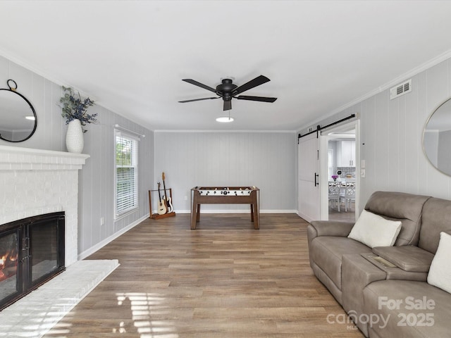 2315 Lawton Bluff Rd, Charlotte, NC 28226 - living area with ornamental molding, a barn door, wood finished floors, ceiling fan, and a fireplace