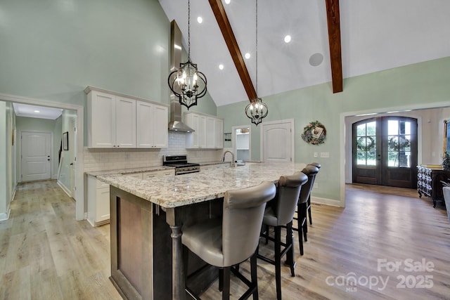 1166 Rocky River Rd, Lancaster, SC 29720 - kitchen with stainless steel gas range, high vaulted ceiling, a kitchen island with sink, white cabinetry, and tasteful backsplash