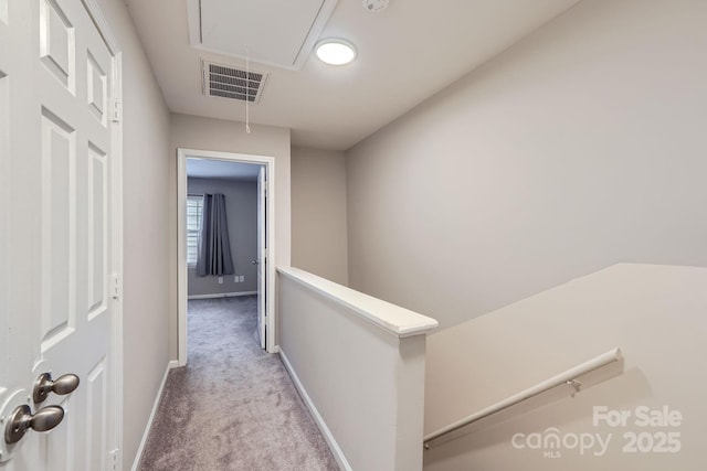 corridor with attic access, carpet, an upstairs landing, and baseboards