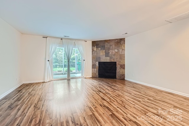 unfurnished living room with wood finished floors, a fireplace, and baseboards