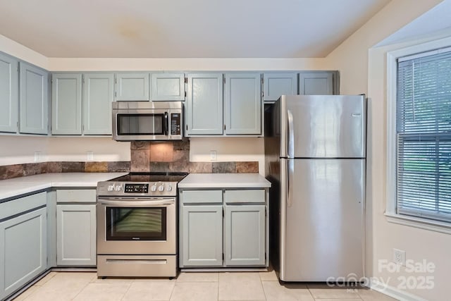 kitchen with stainless steel appliances, plenty of natural light, light tile patterned floors, and light countertops