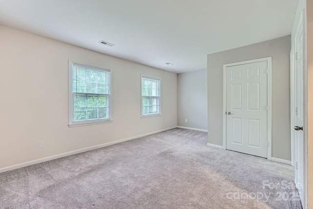 empty room featuring light colored carpet and baseboards