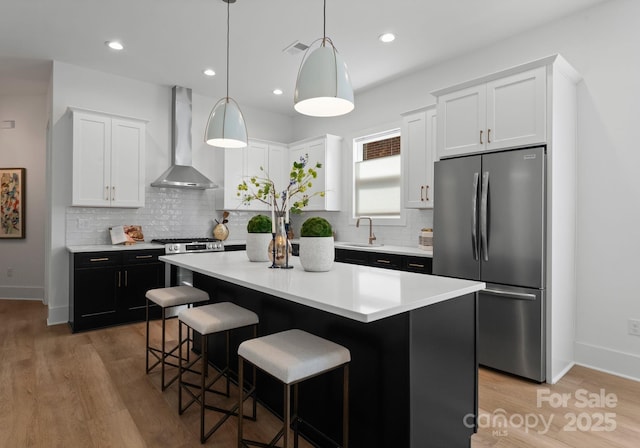 2006 St John St, Charlotte, NC 28216 - kitchen with appliances with stainless steel finishes, wall chimney exhaust hood, decorative backsplash, a kitchen island, and white cabinets