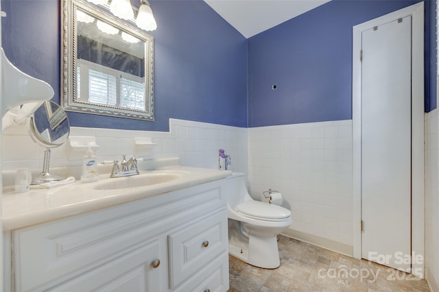 679 Fairforest Rd, Chester, SC 29706 - bathroom featuring tile walls, toilet, vanity, stone finish flooring, and wainscoting