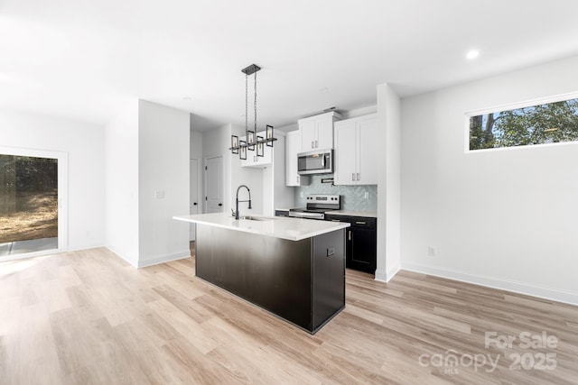 kitchen featuring appliances with stainless steel finishes, a sink, light wood-type flooring, light countertops, and recessed lighting