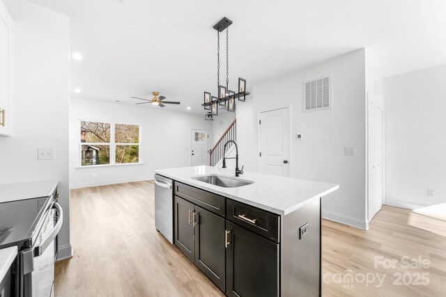 kitchen with a sink, light wood finished floors, ceiling fan, stainless steel dishwasher, and recessed lighting
