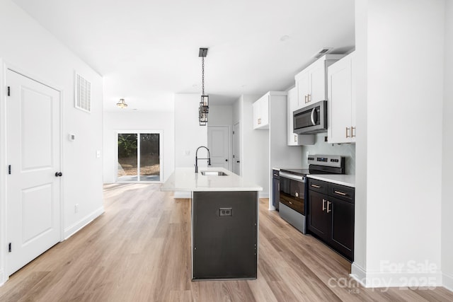 kitchen with stainless steel appliances, a sink, light wood finished floors, light countertops, and white cabinetry
