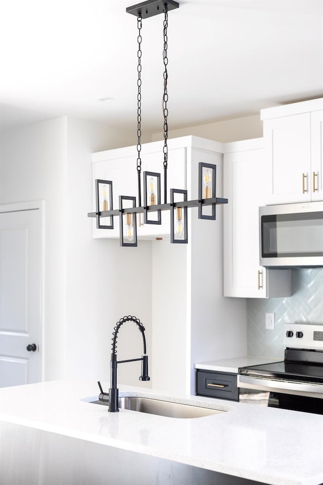 kitchen featuring appliances with stainless steel finishes, a sink, white cabinets, and decorative backsplash